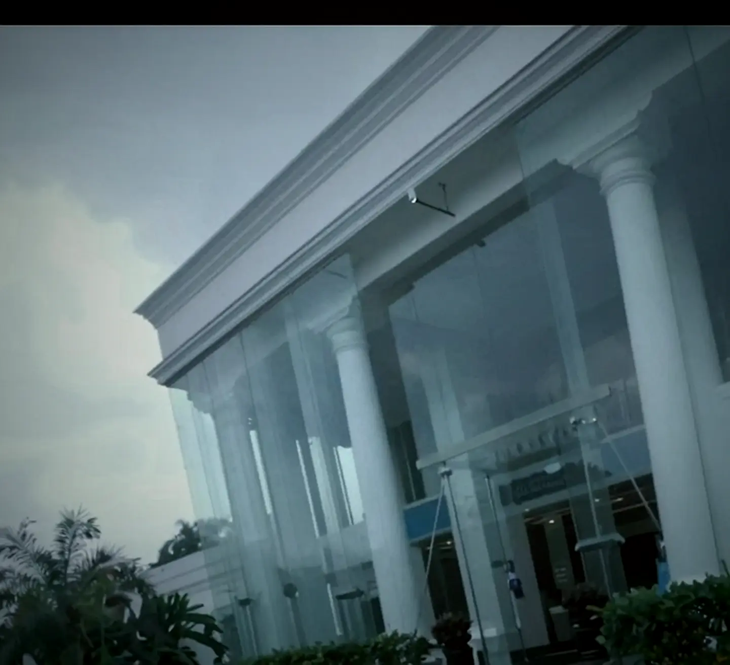 White colonial entrance of OSMO Fitness with columns and a glass atrium wall